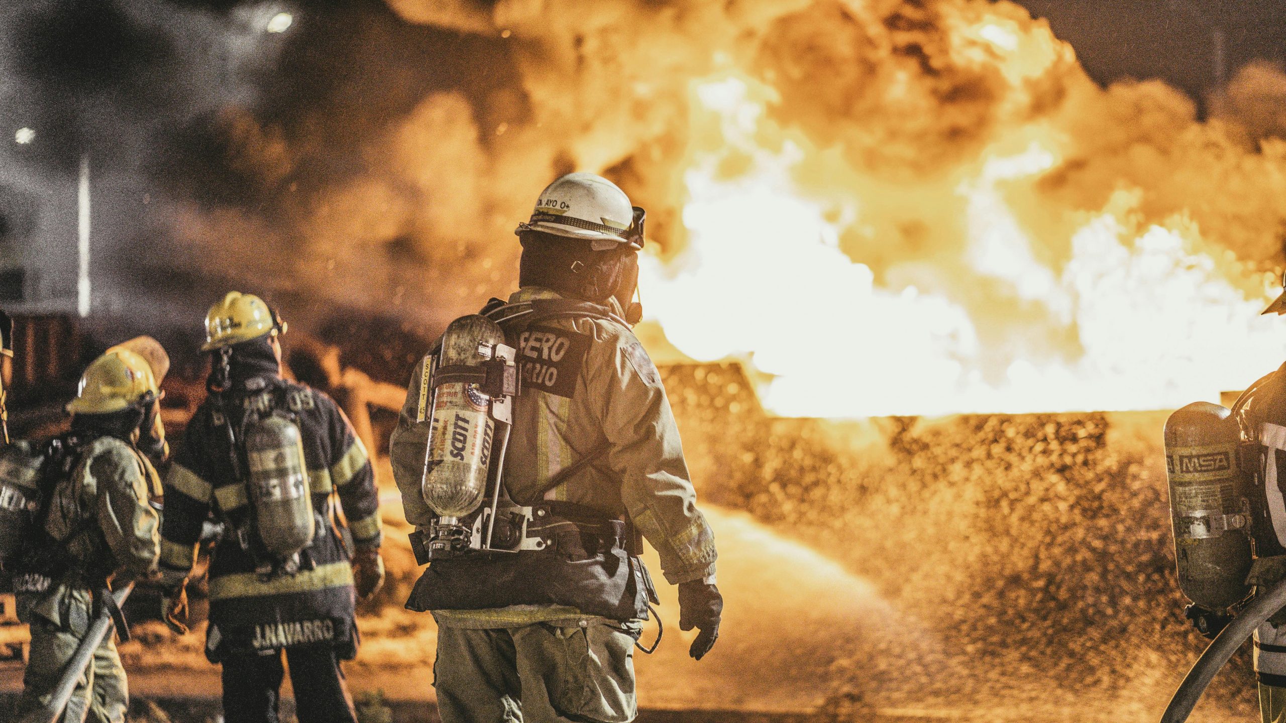 Courageous firefighters actively combat a massive fire, showcasing bravery and teamwork at night.